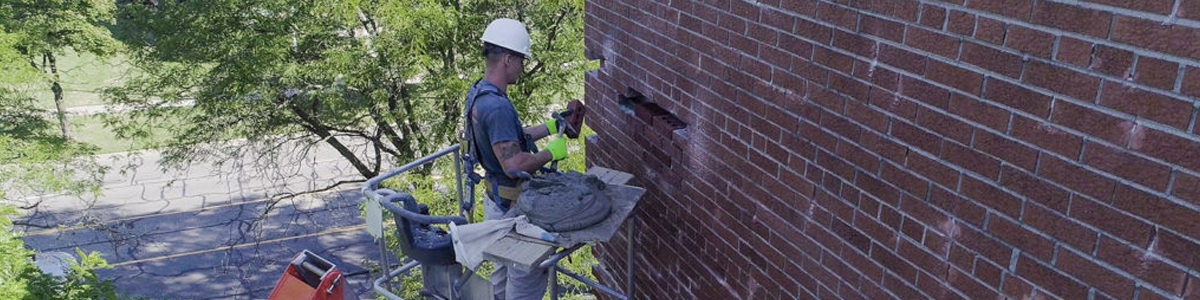 Man in hard hat removing stains from brick wall